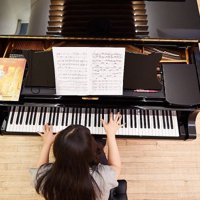 Student sat at a piano. Photograph taken from above their head looking down.